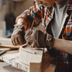 Craftsman cutting a wooden plank. Worker with wood. Man in a cell shirt.